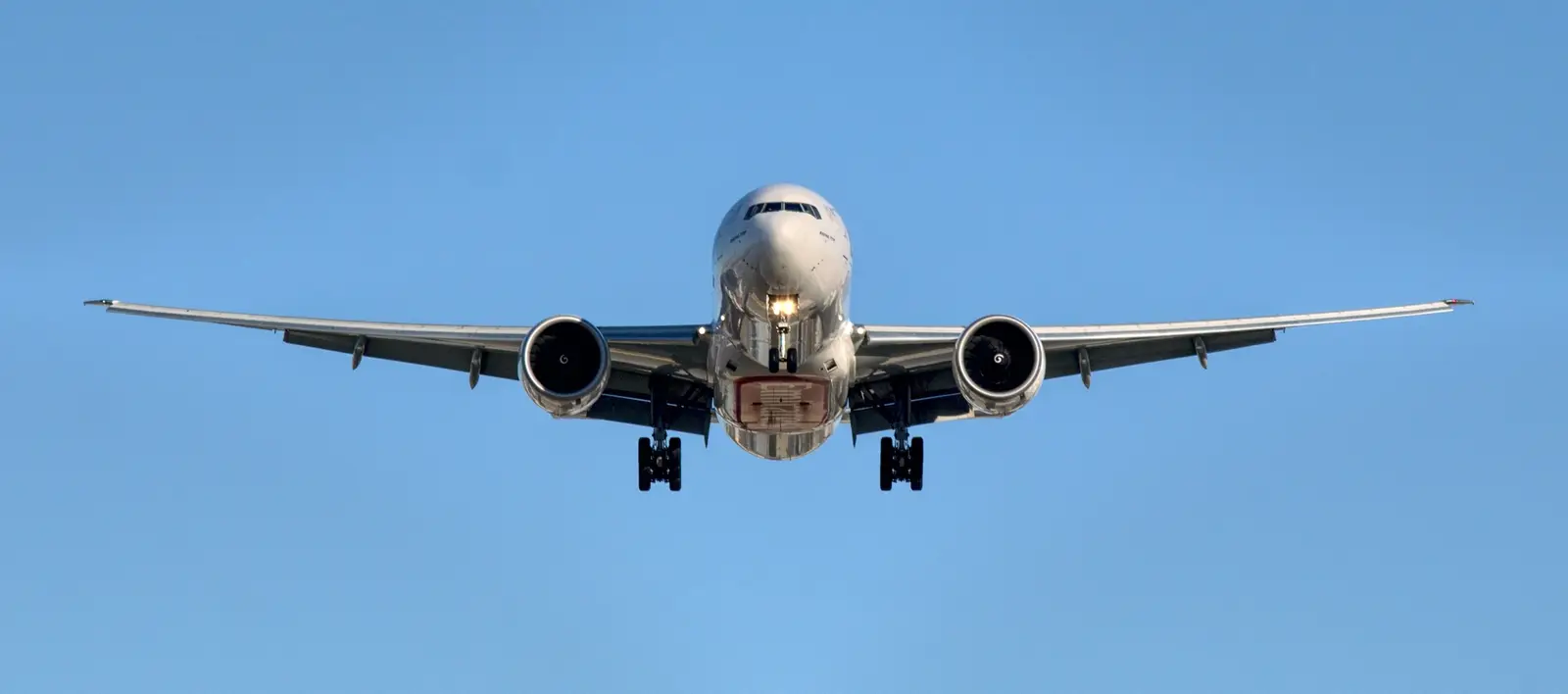 A wide-body freighter aircraft on approach against a clear sky