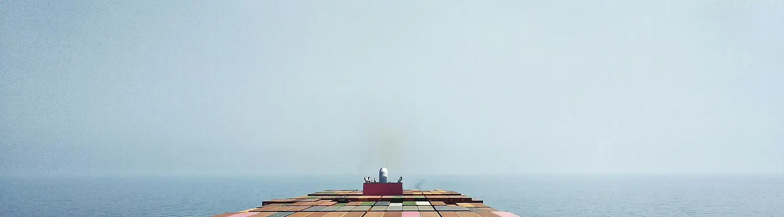 The view forward from the deck of a container ship towards a hazy sea horizon